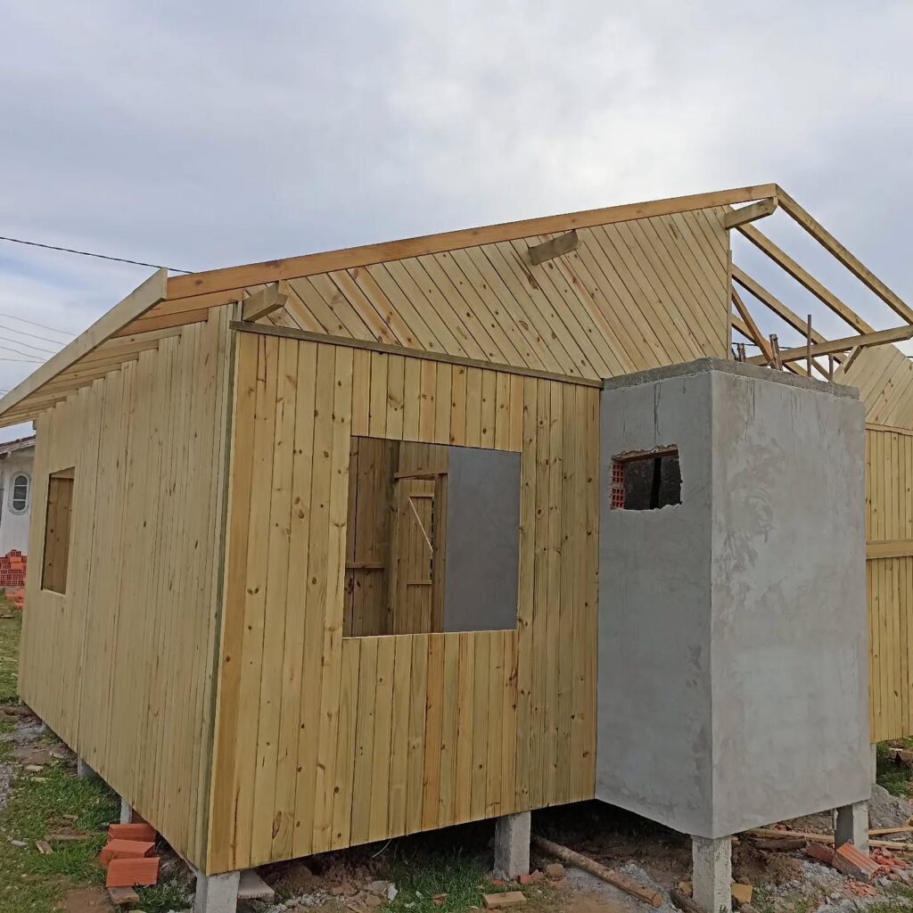 Construção de casas de madeira com estrutura elevada, paredes de madeira e chaminé em alvenaria.