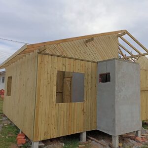 Construção de casas de madeira com estrutura elevada, paredes de madeira e chaminé em alvenaria.