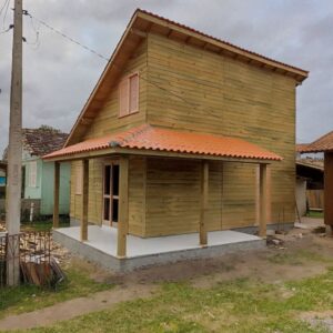 Chalé de madeira com dois andares, varanda coberta e telhado colonial em telhas cerâmicas.